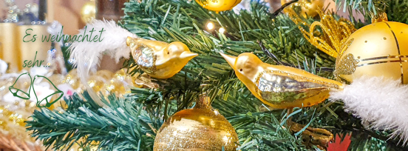 Detail eines Weihnachtsbaum mit zwei goldenen Vögel und goldenen Kugeln der Serie Eleganz aus der Deko in der Weihnachtswelt der ELIAS Glashütte